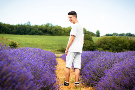 A young guy with a smile in a white shirt stands in a lavender fieldの写真素材
