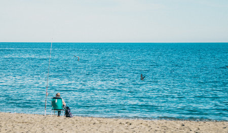 A Peaceful Day at the Beautiful Beach Enjoying Fishing by the Tranquil Sea under the Sunの写真素材