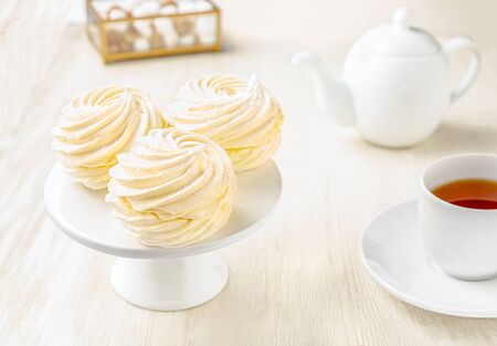 Side view of white marshmallows with tea cup and teapot on white wooden backgroundの写真素材