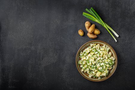 Homemade potatoes salad with Spring Onion with Raw Potatoes on dark stone backgroundの写真素材