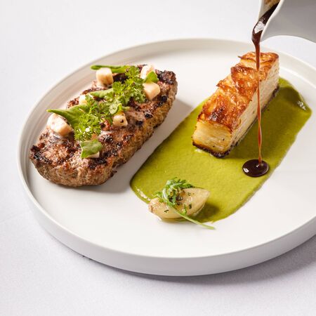 Grilled cutlet on a plate with sauce and gratin. White background.の写真素材