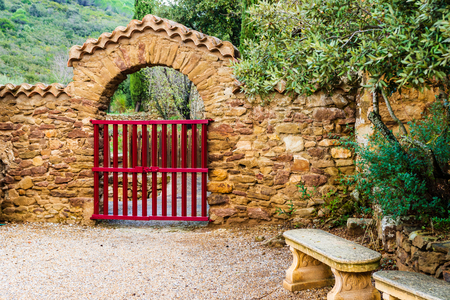 Entrance at Fontfroide Abbey monastery in France. Red gate and stone bench.のeditorial素材