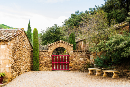 Entrance at Fontfroide Abbey monastery in France. Red gate and stone bench.のeditorial素材