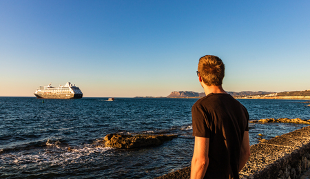 Tourist looking over the olf venetian harbor of Chania in Crete at sunset.の写真素材