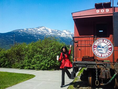 Skagway, Alaska, USA - 2019. Young woman getting down from train cart Yukon Route.のeditorial素材