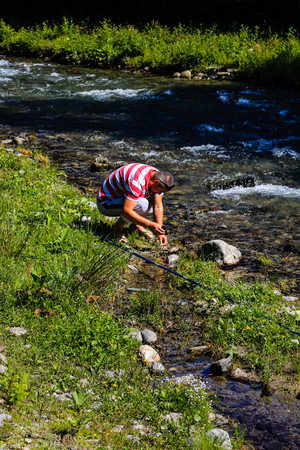 Iezer Mountains - Romania - 2019. Man preparing his bate for fishing in the creek of Rausor Dam in the mountains of Iezer.のeditorial素材