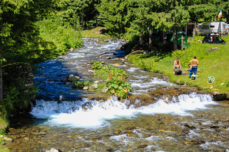Iezer Mountains - Romania - 2019. People relaxing next to a river, and having barbeque.のeditorial素材