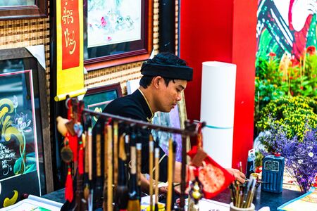 Ho Chi Minh City, Vietnam â 2019. Vietnamese man in ao dai, write Chinese writing or calligraphy at spring fair in Ho Chi Minh, Vietnam.のeditorial素材