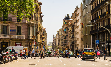 Barcelona, Spain â€“ 2019. People crossing the street on a busy afternoon in downtown...