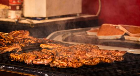 Juicy steaming meat on a charcoal grill, pork steaks, chicken breast, sausages, pieces of meat chops, Romanian minced meat (mici)  at a street food festivalの写真素材