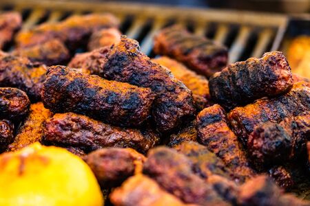 Juicy steaming meat on a charcoal grill, pork steaks, chicken breast, sausages, pieces of meat chops, Romanian minced meat (mici)  at a street food festivalの写真素材