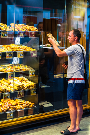 Customer buying fresh baked pastry from a bakery shop in the North Railway Station (Gara de Nord) in Bucharest, Romania, 2019のeditorial素材