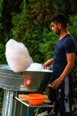 Young man making and selling cotton candy on an alley in the park at a festival in Bucharest, Romania, 2019のeditorial素材