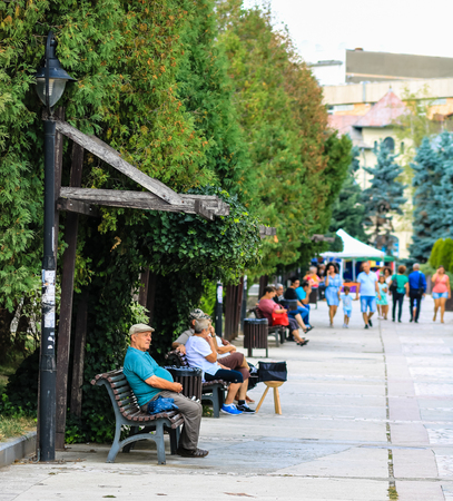 People sitting on wooden bench in central park of Targoviste, Romania, 2019のeditorial素材