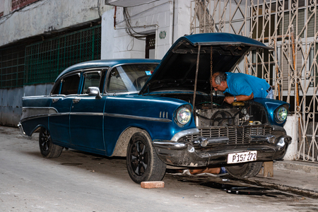 Havana, Cuba â 2019. Man fixing the engine of an old vintage American car on the street.のeditorial素材