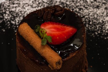 Chocolate mousse with strawberry and chocolate stick on a black dish.の写真素材
