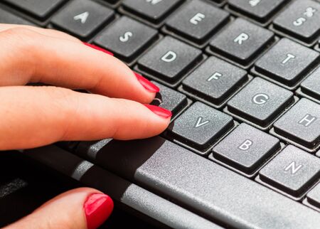 Female hand using pc keyboard. Close up woman hand on computer keyboard on black wooden backgroundの写真素材