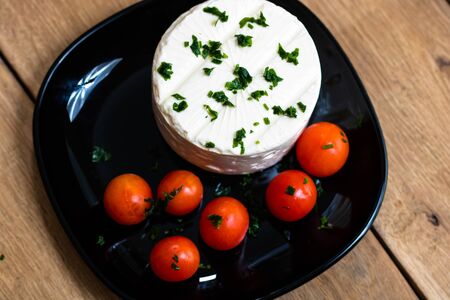 Breakfast food, cheese and cherry tomatoes on dish, on a rustic wooden plank board table background.の写真素材