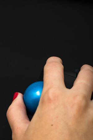 Female hand using pc mouse. Close up woman hand on computer mouse on black wooden backgroundの写真素材