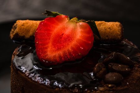 Chocolate mousse with strawberry and chocolate stick on a black dish.の写真素材