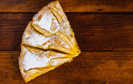 Freshly baked apple pie with sugar powder on a wooden board. Homemade apple cake.