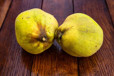 Isolated quinces. Two yellow quinces on a wooden board.の写真素材