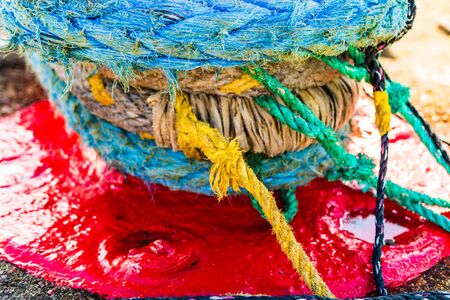 Harbor marina detail. Old rusty mooring bollard with rope. Berth in the passenger port. Mooring points.の写真素材