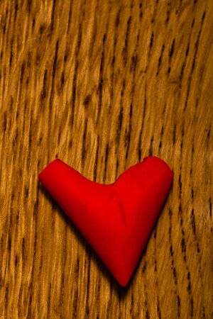 Close up of a red rose petal. Heart shaped red rose petal on a wooden board.の写真素材