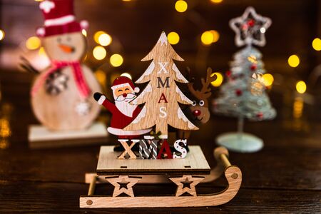 Christmas decorations against blurred background. Close up of a wooden Christmas sledge with Santa Claus, a reindeer and Christmas tree.の写真素材