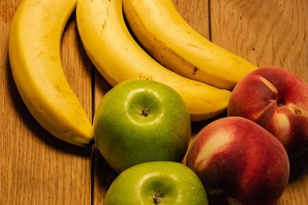 Apple, peach and bananas on a wooden board. Composition of healty fruits.の写真素材