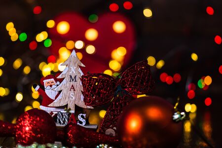 Christmas decorations against blurred background and out of focus lights. Close up of a wooden Christmas sledge with Santa Claus, a reindeer, Christmas tree and glittery Christmas ballsの写真素材