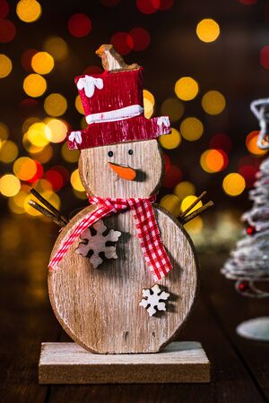 Christmas decorations against blurred background and out of focus lights. Decorative wooden snowman and glittery Christmas ballsの写真素材