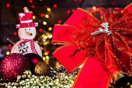 Christmas decorations against blurred background and out of focus lights. Decorative wooden snowman and glittery Christmas ballsの写真素材