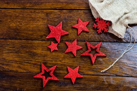 Christmas burlap sack with glittery and shiny Christmas decorations. Christmas decorations on wooden board. Red Christmas stars and snowflakes.の写真素材