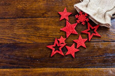 Christmas burlap sack with glittery and shiny Christmas decorations. Christmas decorations on wooden board. Red Christmas stars and snowflakes.の写真素材
