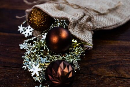 Christmas burlap sack with glittery and shiny Christmas decorations. Christmas decorations on wooden board.の写真素材