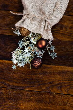 Christmas burlap sack with glittery and shiny Christmas decorations. Christmas decorations on wooden board.の写真素材