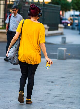 Young girl listening music while walking with a coffee cup in her hand in Bucharest, Romania, 2019のeditorial素材