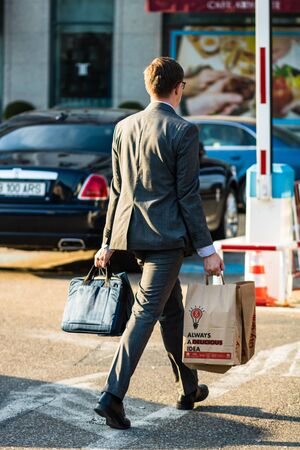 Young man in business suit carrying bag of take away food in downtown area of Bucharest, Romania, 2019のeditorial素材