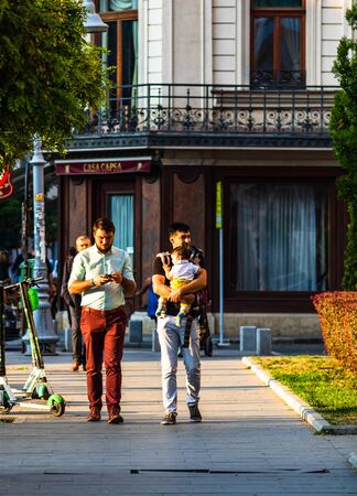 Man, father holding baby, walking down the street next to his friend, visiting Bucharest, Romania, 2019のeditorial素材