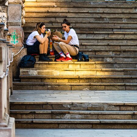 Girls having lunch on the stairs in old town in Bucharest, Romania, 2019のeditorial素材
