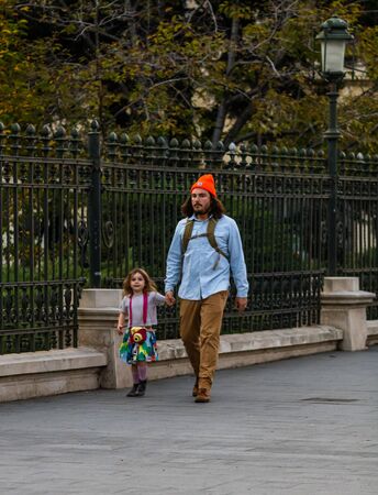 Father walking with his young daughter on the sidewalk of Victoriei Way (Calea Victoriei) in downtown Bucharest, Romania, 2019のeditorial素材