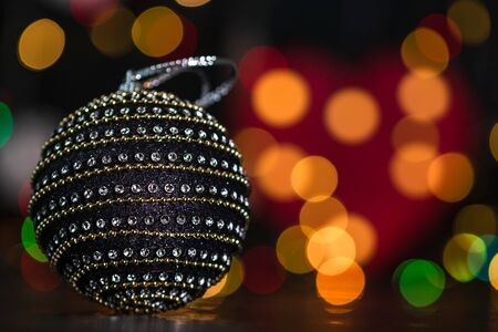 Christmas decoration and ornaments. Christmas composition on blurred lights background. Black and shiny Christmas ball.の写真素材