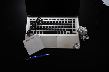 Different objects on black office desk. Modern black office desk table with laptop keyboard, mouse,...