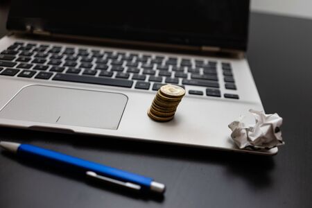 Close up of Coins on laptop keyboard. Different objects on black office desk.の写真素材