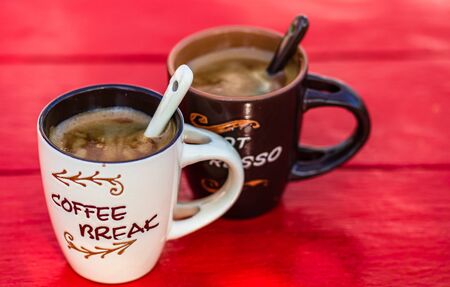 Two cups of homemade expresso coffee on red wooden board.の写真素材