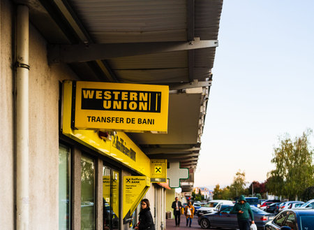 The exterior of a Western Union store in Bucharest. Young girl at the ATM in Bucharest, Romania,...