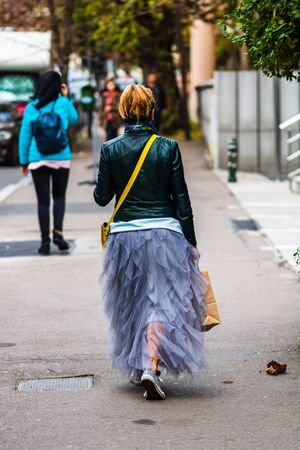 Young hipster girl walking on the sidewalk with grey dress on an autumn morning in Bucharest, Romania, 2019のeditorial素材