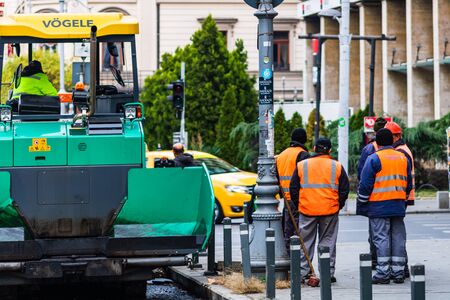 Workers in overalls in an autumn morning repair the street on the main boulevard Victoriei (Calea Victoriei) in downtown Bucharest, Romania, 2019のeditorial素材