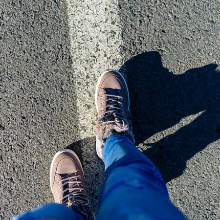 Top view of woman boots with shadows. Woman walking on the street.の写真素材